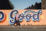 Graffiti says Good in blue letters on orange wall