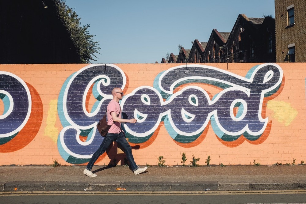 Graffiti says Good in blue letters on orange wall