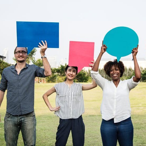 Three people, one male and two female, holding up conversation signs