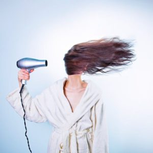 Woman in bathrobe dry blowing her hair sideways