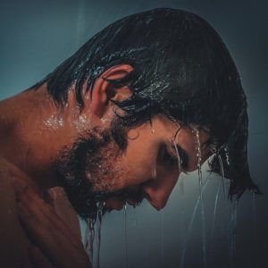 Man with black hair in shower