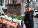 Woman in wintercoat looking at vegetable stall