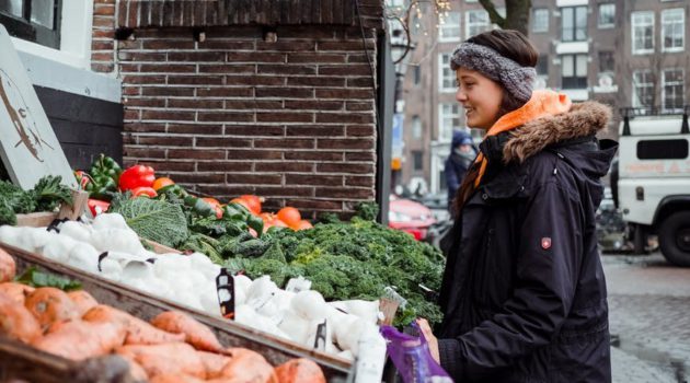 Woman in wintercoat looking at vegetable stall