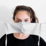 Dark haired woman putting on a face mask