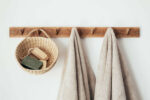 Two beige towels and a natural basket hanging on a wooden coat rack